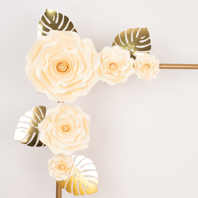 Cream paper flowers with gold leaves arranged decoratively.