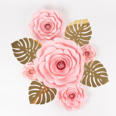 Pink paper roses with gold leaves on a white background.