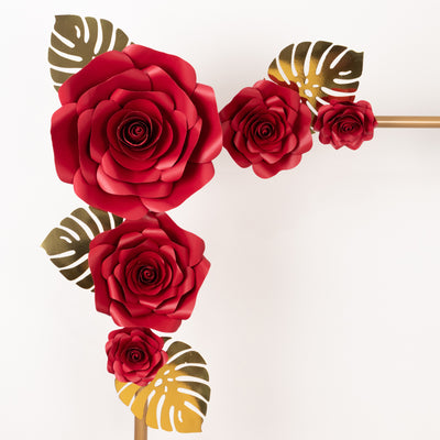 Red paper roses with gold leaves on a decorative frame.