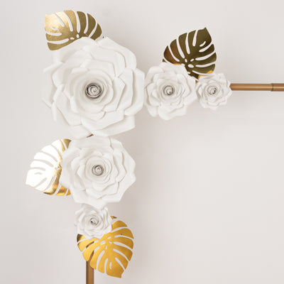 White and gold floral wall decor with leaves on a plain background
