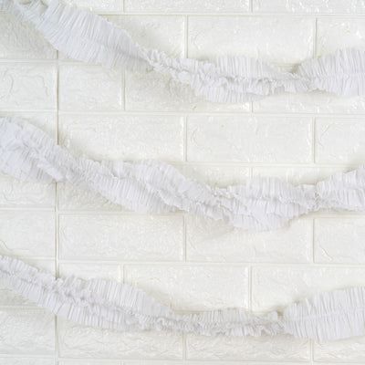 White ruffled garland decoration on a textured white background.