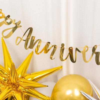 Gold anniversary banner with decorative stars and balloons in a festive setting.