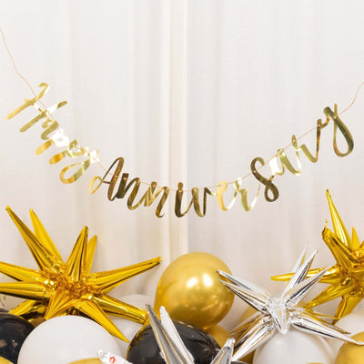 Gold "Happy Anniversary" banner with balloons and star decorations.