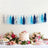 Colorful party decoration tassel garland with cake and desserts on a festive table.