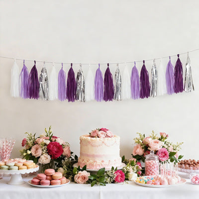 Purple and silver party decorations with cake and desserts on a table.