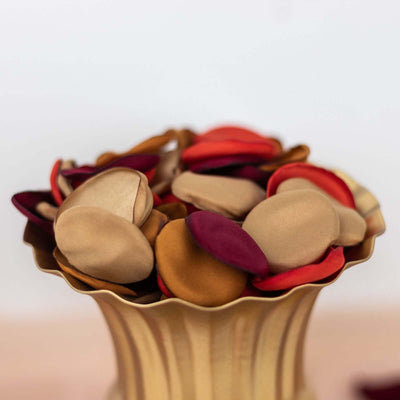 Colorful fabric petals in a decorative gold vase.