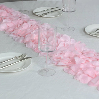 Pink rose petal table runner with elegant white dining place settings