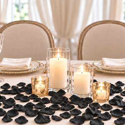 Elegant candlelit table setting with black petals and gold-rimmed plates
