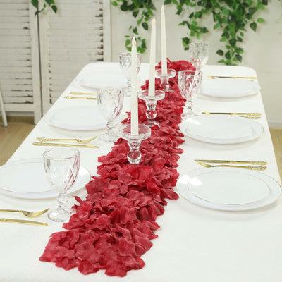 Elegant red rose petal table runner with white candles and gold place settings