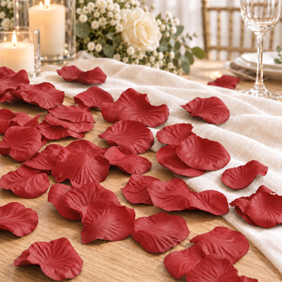 Romantic table setting with red rose petals, candles, and floral centerpiece