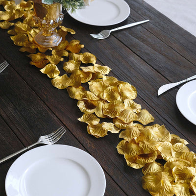 Gold leaf table runner on dark wood dining table with white plates and silverware