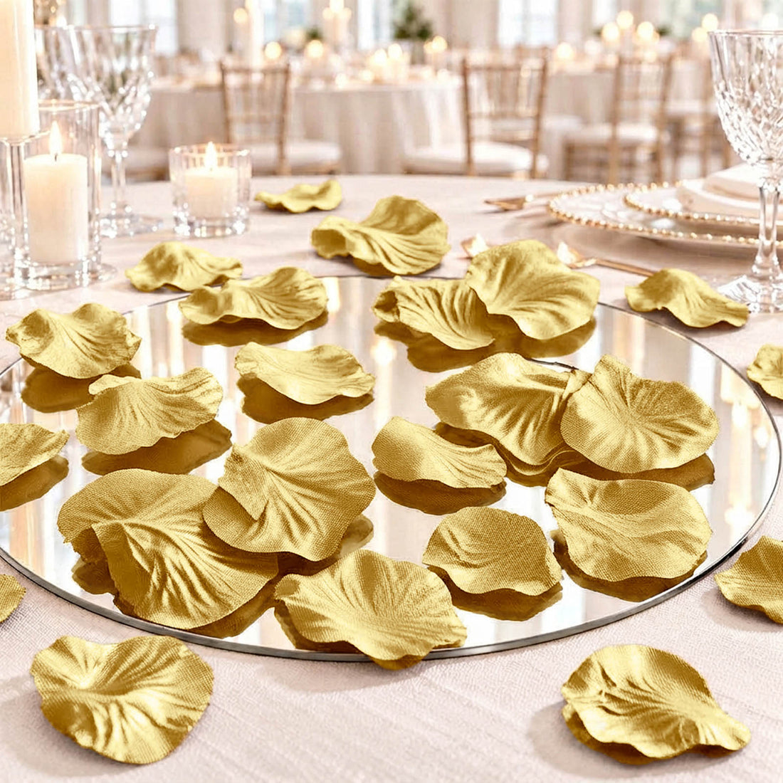Gold flower petals on a mirrored table centerpiece at an elegant wedding reception