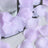 Lavender rose petals on textured fabric with glass vase centerpiece