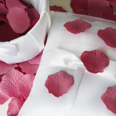 Pink silk pillow with rose petals for wedding decor.