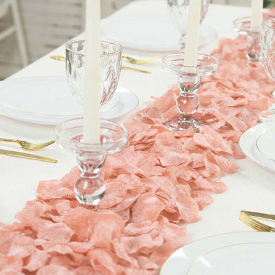Elegant table setting with pink petal runner, gold flatware, and glass candle holders