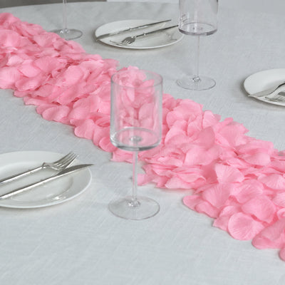 Pink petal table runner on white dining table with glassware and silverware