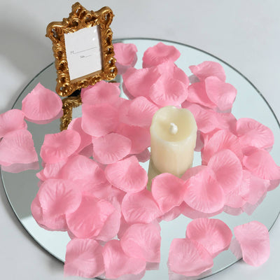 Pink rose petals on mirrored table with candle and ornate gold frame