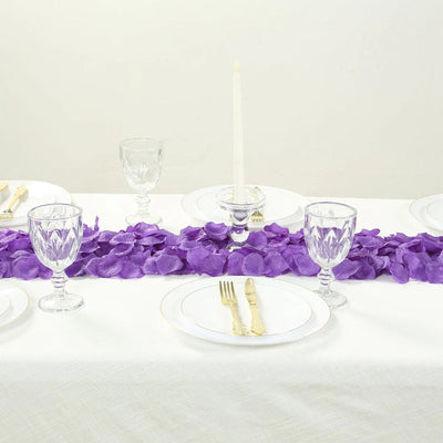 Elegant white table setting with purple petal runner, glassware, and gold flatware