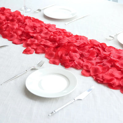 Red rose petal table runner on white table setting with plates and silverware