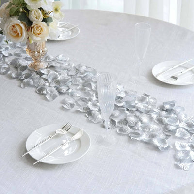 Elegant white wedding table setting with floral centerpiece and silver leaf runner