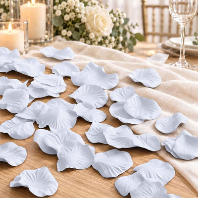 White artificial flower petals on wedding table decor with candles and roses