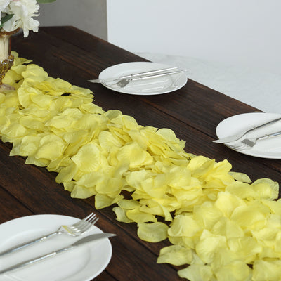 Yellow rose petals arranged on a wooden table with plates and cutlery.