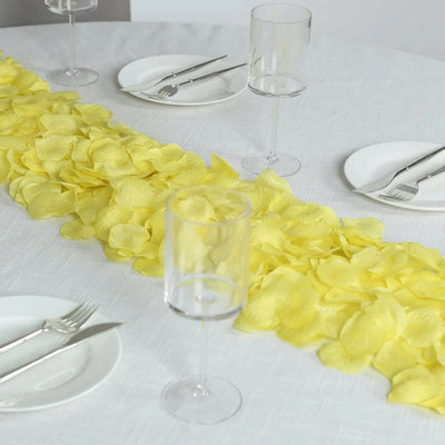Yellow petal table runner on white banquet table with glassware and silverware