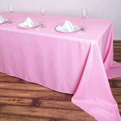 Pink tablecloth draped over a table set for dining with plates and glasses.