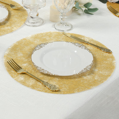 Elegant gold placemat with white plate and gold utensils on a dining table.