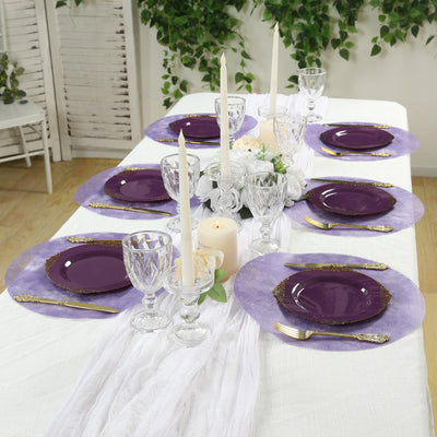 Elegant purple dinnerware set on a beautifully arranged table with candles and decor.
