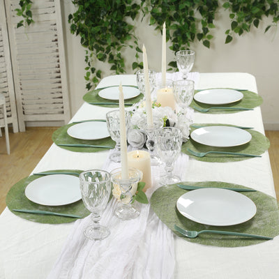 Elegant dining table setting with green placemats and white dishware, adorned with candles.