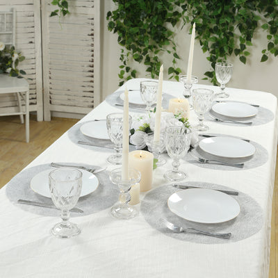 Elegant dining table set with white plates, crystal glasses, and candles.