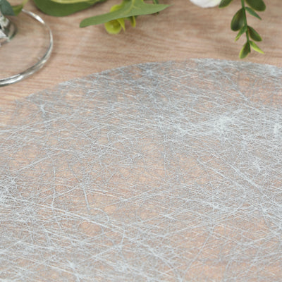 Elegant silver placemat with textured design on a wooden table.
