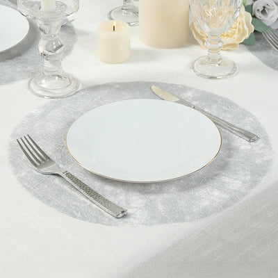 Elegant silver placemat with white plate and cutlery on a dining table setting.