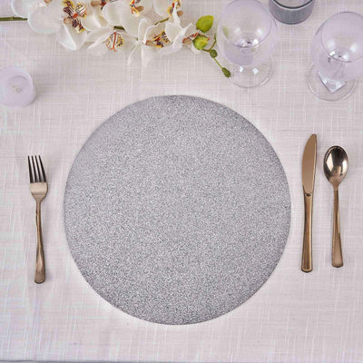 Gray round placemat with utensils on a textured table setting.