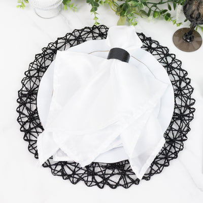 Elegant white napkin on a black woven placemat with a decorative plate.