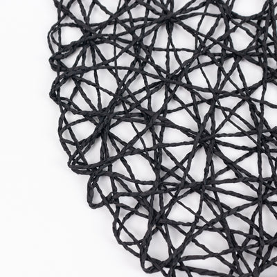 Black woven placemat with intricate geometric design.