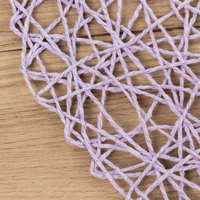 Close-up of a lavender-colored woven net texture on a wood surface.