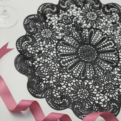 Black lace doily with decorative floral pattern and pink ribbon accents.