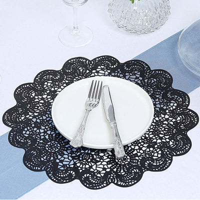 Black lace table placemat with a white plate and silver cutlery on a dining table.