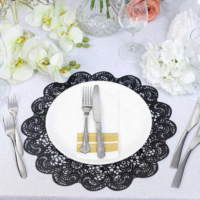 Elegant black lace table mat with a white plate and silver cutlery on a festive table setting.