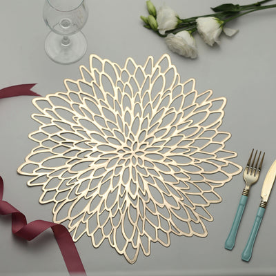 Decorative gold flower placemat on a table with cutlery and wine glass.