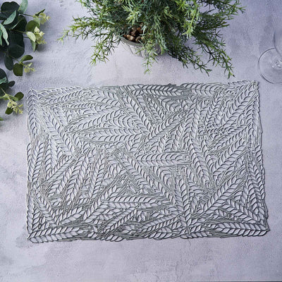Decorative lace placemat with leaf design on a textured surface.