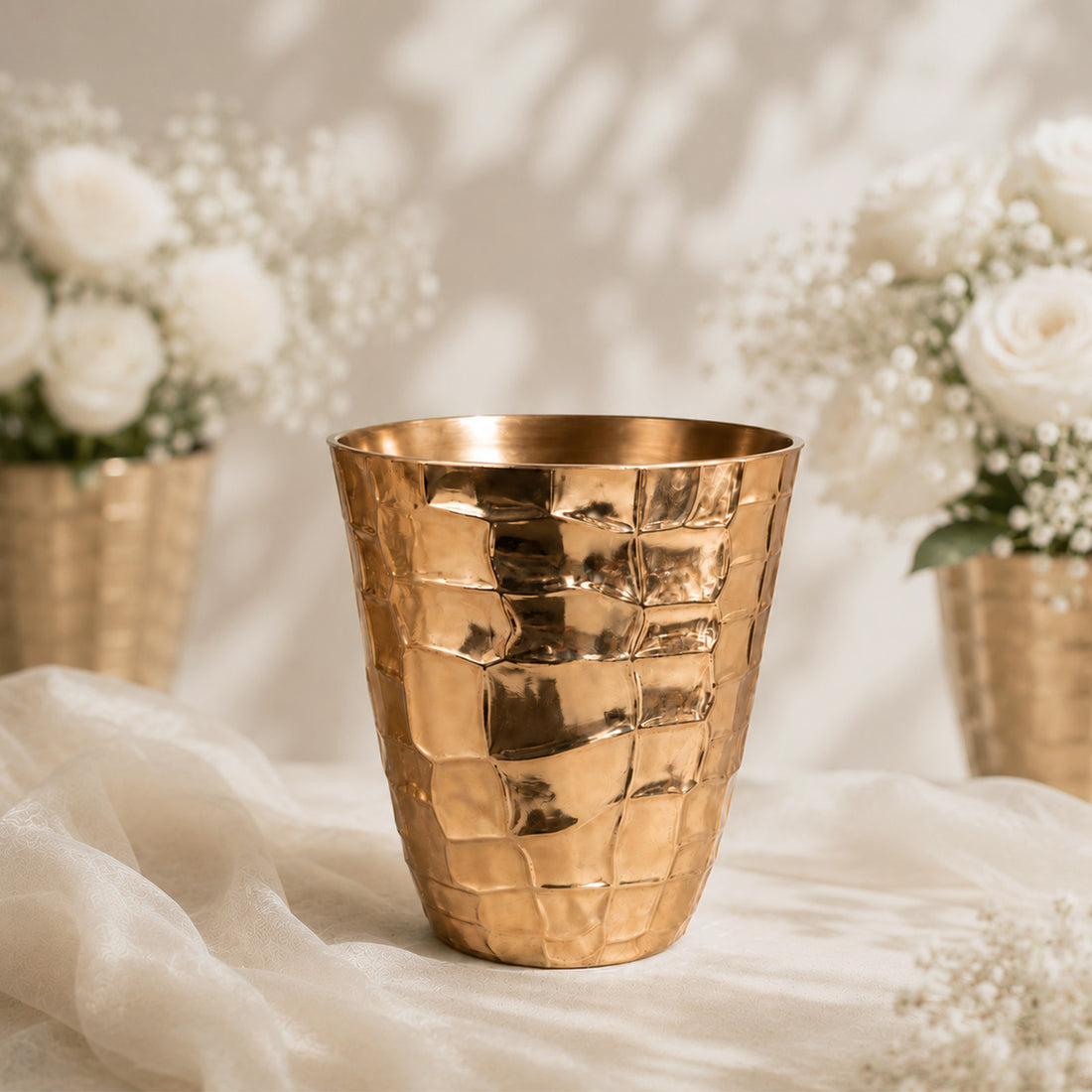 Gold textured vase with white roses and baby’s breath on a soft backdrop