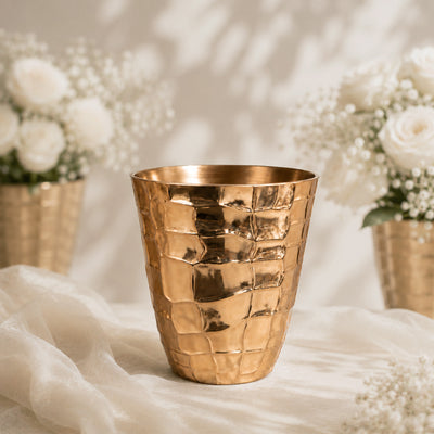 Gold textured vase with white roses and baby’s breath on a soft backdrop