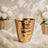 Gold textured vase with white roses and baby’s breath on a soft backdrop