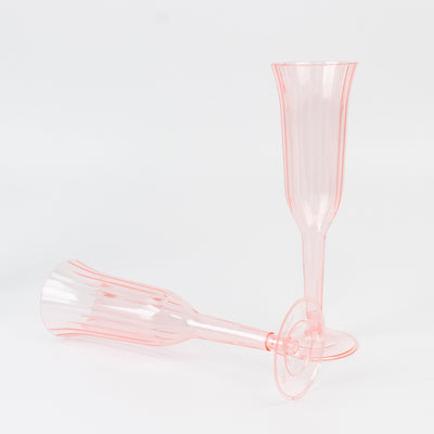 Pink plastic champagne flutes on a white background