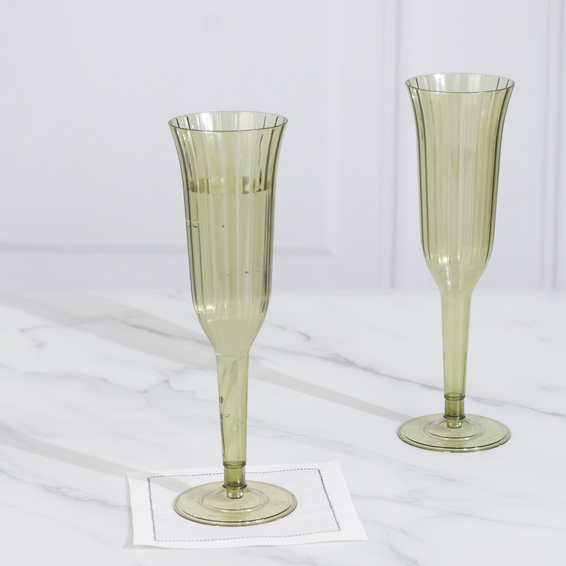 Green ribbed champagne flutes on a marble surface