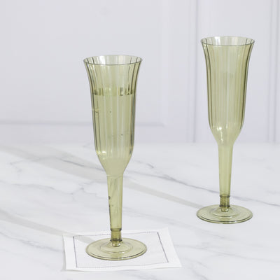 Green ribbed champagne flutes on a marble surface