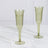 Green ribbed champagne flutes on a marble surface